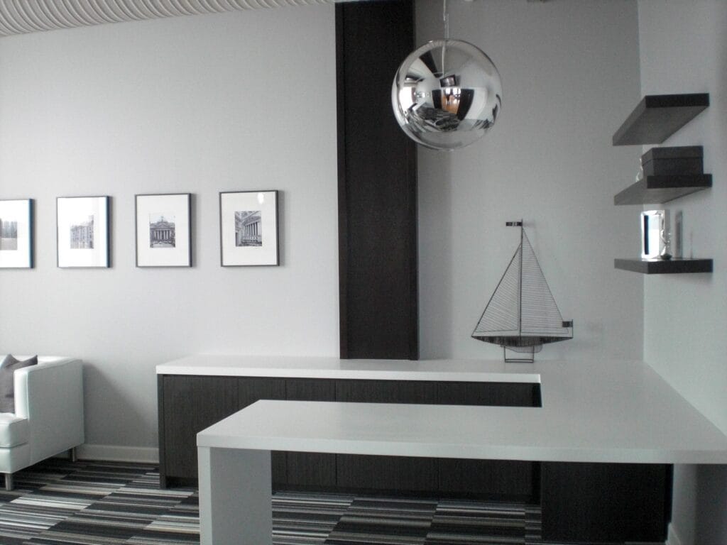 Modern trading office interior with minimalist executive workspace featuring white desk surfaces dark wood cabinetry floating shelves and contemporary pendant lighting in a loft-style office design